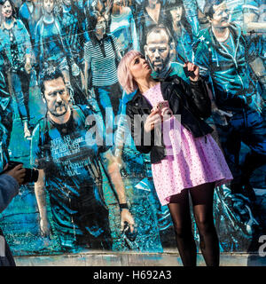 New York, NY 23 October 2016 - Woman in Pink taking a selfie in front of  Logan Hicks' mural entitled Story Of My Life . The mural features a crowd of people he photographed on the corner of Spring and Greene Street. Stacy Walsh Rosenstock Stock Photo