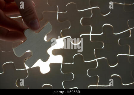 Woman placing missing piece in Jigsaw puzzle Stock Photo
