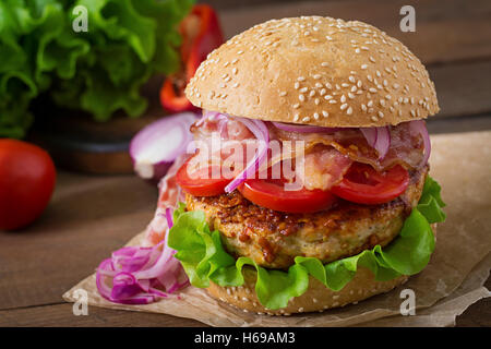 Big sandwich - hamburger burger with beef, red onion, tomato and fried bacon. Stock Photo