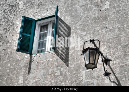 a window with green shutters and a lantern on an old house Stock Photo