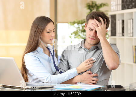 Doctor examining a patient auscultating with a stethoscope in an office interior Stock Photo