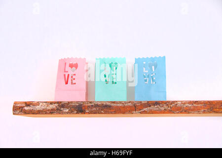 Tealight candle bags love heart colorful wood shelf wall wooden board on a white white pink pink petrol green light green blue l Stock Photo