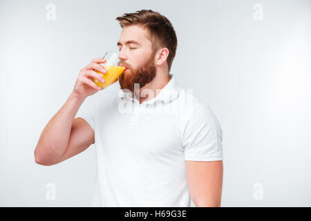 Young handsome bearded man drinking orange juice isolated on white background Stock Photo