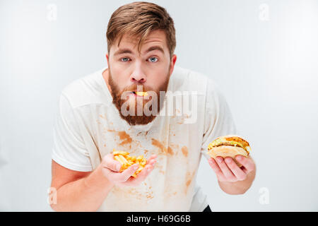Funny hungry bearded man eating junk food isolated on white background Stock Photo