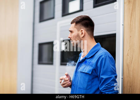 auto mechanic smoking cigarette at car workshop Stock Photo