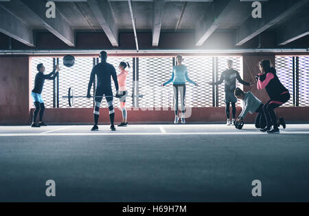 Group of diverse friends working out in town in a commercial building doing a variety of different exercises weightlifting, skip Stock Photo