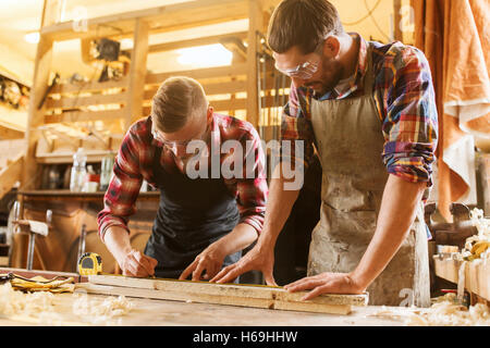 carpenters with ruler and wood plank at workshop Stock Photo