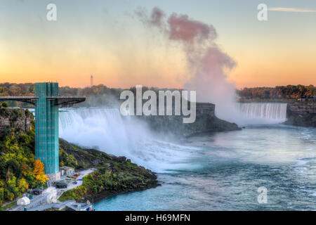Light from the rising sun reflects off the spray from Horseshoe Falls with the American Falls on the left in Niagara Falls. Stock Photo