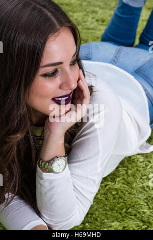 beautiful brunette with dark purple lips and straight hair sitting on the floor Stock Photo