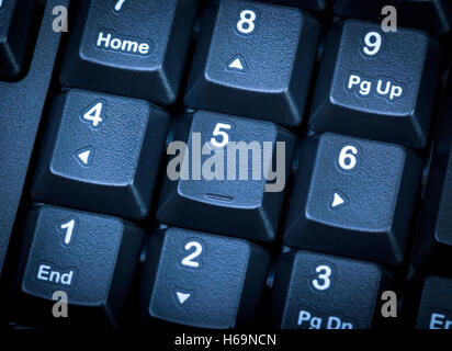Electronic collection - detail numeric keypad on the black computer keyboard. Focus on the center key. Toning is blue. Stock Photo