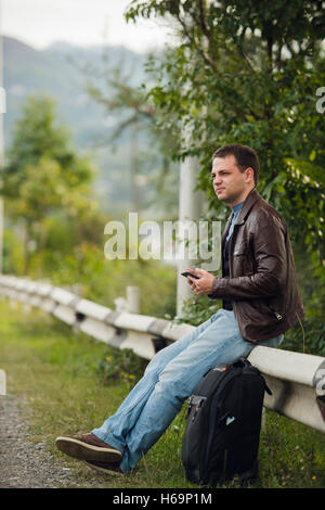 Man sitting on a road fence with gps tablet pc and using online maps Stock Photo