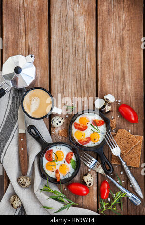 Fried eggs with tomatoes in frying pans served for breakfast Stock Photo