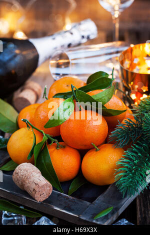 Holiday concept: fresh tangerines, cork, glass, champagne, candles and garlands Stock Photo