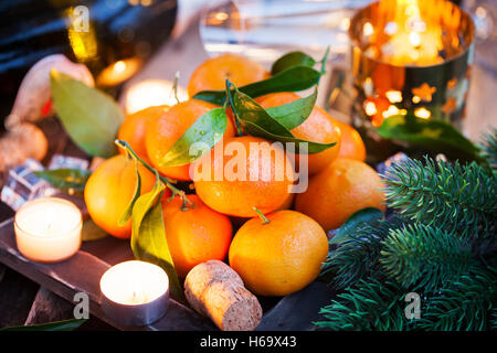 Holiday concept: fresh tangerines, cork, glass, champagne, candles and garlands Stock Photo