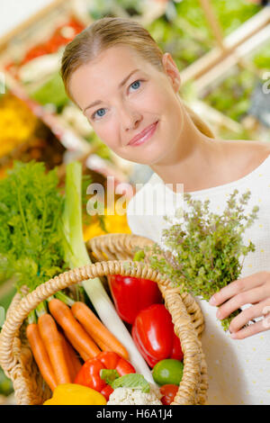 Lady adding herbs to purchases in a basket Stock Photo