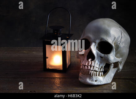 Human skull on floor next to lantern Stock Photo