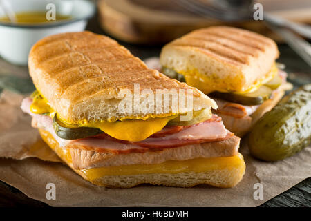 An authentic cuban sandwich on pressed medianoche bread with pork, ham, cheese, pickle, and mustard. Stock Photo