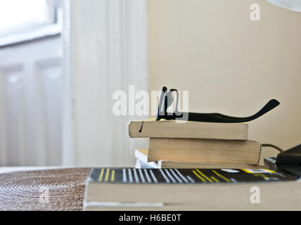 Closeup of stack of books with reading glasses Stock Photo