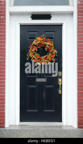 Fall wreath on a brick home's white framed black door. Stock Photo