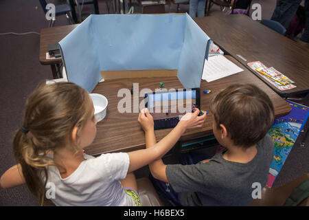Two elementary school students collaborate on a class digital animation project in Mission Viejo, CA. Note desktop background, digital camera, and objects to be animated. Stock Photo