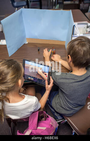 Two elementary school students collaborate on a class digital animation project in Mission Viejo, CA. Note desktop background, digital camera, and objects to be animated. Stock Photo