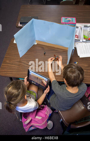 Two elementary school students collaborate on a class digital animation project in Mission Viejo, CA. Note desktop background, digital camera, and objects to be animated. Stock Photo