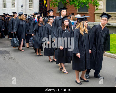 Wearing graduation caps and gowns, multiracial Harvard University graduates form a procession in Harvard Yard in Cambridge, MA. Stock Photo