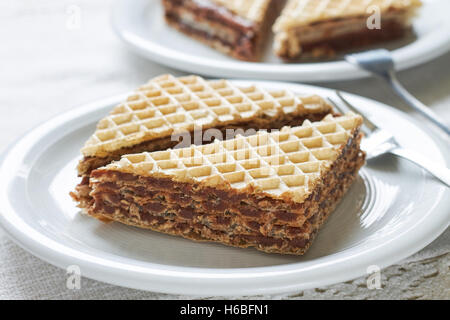 Wafer sheets filled with caramelized sugar and hazelnut cream served on white plate Stock Photo