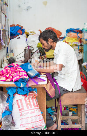 Indian man using a sewing machine in a back street near to the Kapaleeshwarar Temple, Mylapore, Chennai, Tamil Nadu, India Stock Photo
