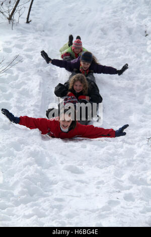 Group of children sliding down on snow Stock Photo
