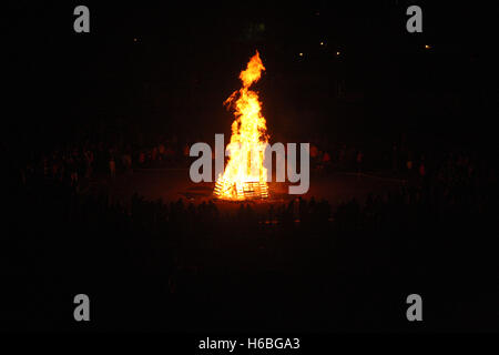 Large camp fire in the dark, surrounded by crowd Stock Photo