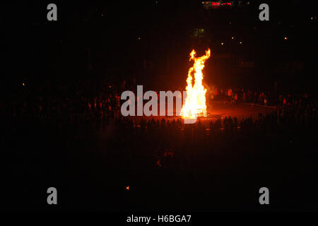 Large camp fire in the dark, surrounded by crowd Stock Photo