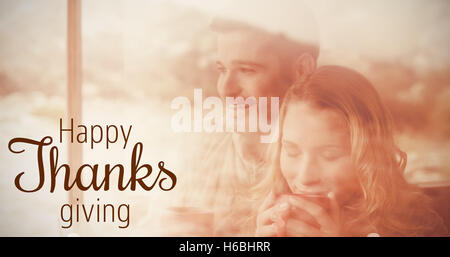 Composite image of thoughtful couple with coffee cups seen through cabin window Stock Photo