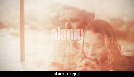 Thoughtful couple with coffee cups seen through cabin window Stock Photo