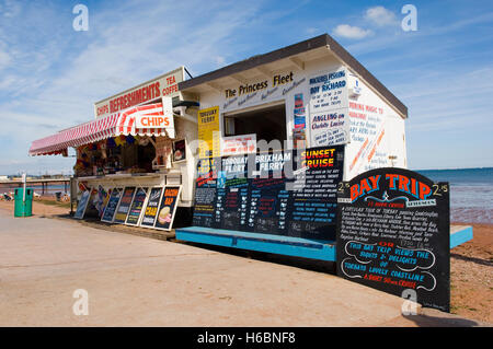 Colourful kiosks selling refreshments boat trips and angling expeditions on the beach at Paignton, Devon on a sunny summer's day Stock Photo