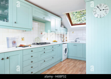 A contemporary, fresh kitchen incorporating an integrated oven, cooker, hood & work surfaces. Gloucestershire, UK Stock Photo