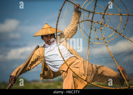 Close up of a burmese fisherman on a traditional bamboo boat using a handmade net