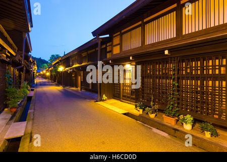 Traditional Japanese dark wooden buildings illuminated at night line pedestrian street in Kamisannomachi Takayama old town Stock Photo