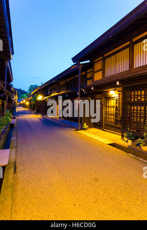 Traditional Japanese dark wooden homes, restaurants lighted at night line empty pedestrian street in Kamisannomachi Takayama Stock Photo