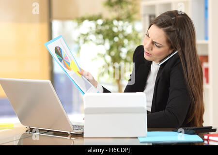 Angry businesswoman calling on the phone while is watching documents at office interior Stock Photo
