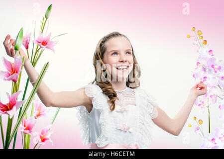 Close up portrait of happy young communion girl among flowers. Stock Photo