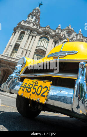 HAVANA, CUBA - JUNE 13, 2011: Bright yellow vintage American car stands parked in front of the landmark Great Theater of Havana. Stock Photo