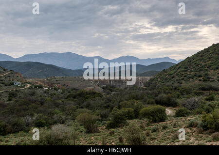 Dam wall at Calitzdorp, cloudy with mountains in the background. Stock Photo