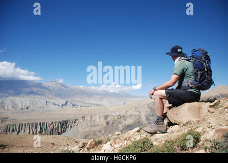 a trekker looks at the view in The Barren mountain landscape of the remote Damodar Himal in the Mustang region of Nepal Stock Photo