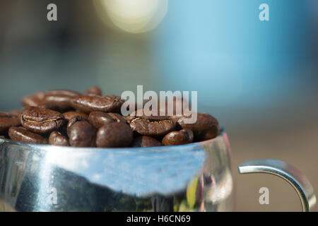 Close up shot of richly roasted coffee beans spilling out of stainless steel espresso cup Stock Photo