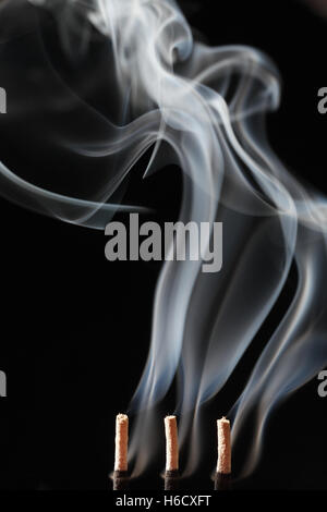 Smoke rising from three incense sticks Stock Photo