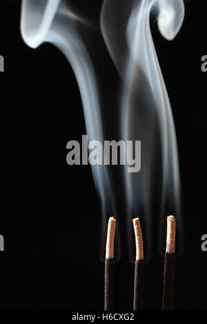 Smoke rising from three incense sticks Stock Photo