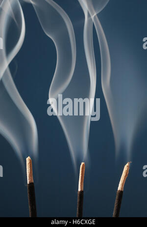 Smoke rising from three incense sticks Stock Photo