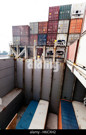 View of a freighter ship's storage compartment, half full with containers, in the middle of the loading process. Stock Photo