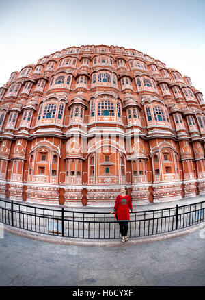 Woman in red dress with scarf standing near façade of Hawa Mahal, Rajasthan, India